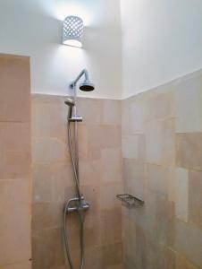 een douche met een douchekop in de badkamer bij Kaia Lovina Guest House in Lovina