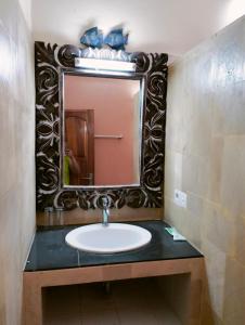 Kaia Lovina Guest House في لوفينا: حمام مع حوض ومرآة