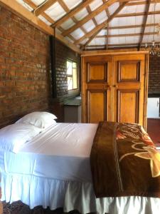 a bedroom with a white bed with a brick wall at African feel studio with kitchenette - 2045 in Harare