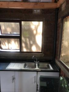 a kitchen with a sink and two windows at African feel studio with kitchenette - 2045 in Harare