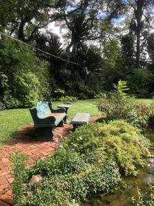 two benches sitting on a brick path in a garden at African feel studio with kitchenette - 2045 in Harare