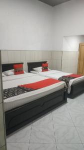 a room with three beds with red sheets at Vina Vira Hotel in Hagu