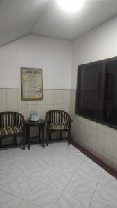 two chairs and a table in a room with a tv at Vina Vira Hotel in Hagu