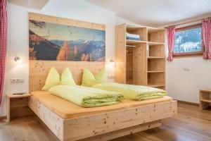 een slaapkamer met een houten bed met gele kussens bij Mountainfarm Innertrein Jöchl in Cadipietra