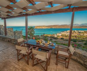 einen Tisch und Stühle auf einer Terrasse mit Meerblick in der Unterkunft Elounda Maris Villas in Elounda