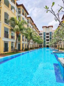 a large swimming pool with palm trees in front of buildings at Balini Home Tiara Desaru in Desaru