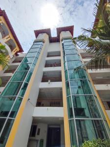 a tall building with glass windows and a palm tree at Balini Home Tiara Desaru in Desaru