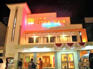 班贾尔马辛Citra Raya Hotel Banjarmasin的一座建筑,人们在晚上站在外面