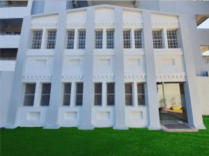 兰奇Hotel Soneva Inn的前面有绿草的白色建筑