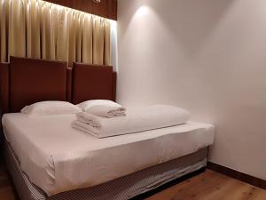 1 dormitorio con 1 cama con sábanas y almohadas blancas en STAYMAKER Hotel Mohan Palace, en Baharampur