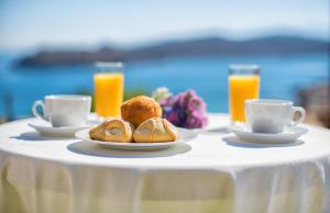 a table with plates of pastries and cups of orange juice at Elounda Maris Villas in Elounda
