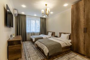 a bedroom with two beds and a chandelier at Oscar Hotel in Almaty