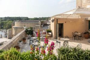 un patio esterno con tavoli, sedie e fiori di Palazzo De Mori a Otranto