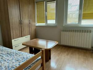 um quarto com uma mesa, uma cama e janelas em Homy apartment in city center Marijin Dvor em Saraievo