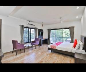 a bedroom with a bed and a desk and chairs at HOTEL ADITYA in Sasan Gir