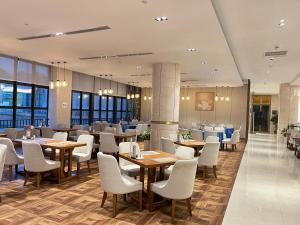 a restaurant with wooden tables and white chairs at Guangzhou Nanhong Ausotel Hotel in Guangzhou
