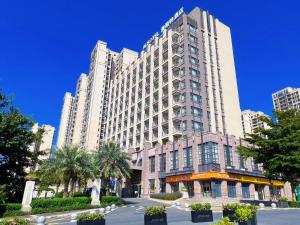 a large white building with palm trees in front of it at Guangzhou Nanhong Ausotel Hotel in Guangzhou