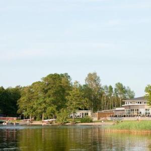 a view of a lake with a house in the background at Ringsjöstrand Hotel in Hörby