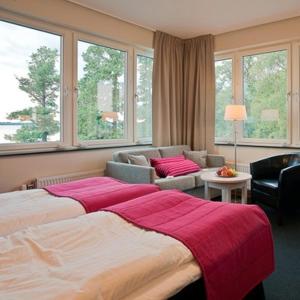 a bedroom with a large bed and a living room at Ringsjöstrand Hotel in Hörby