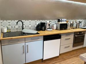 a kitchen with a counter with a sink and a microwave at L Atypik à L ancienne forge in Muhlbach-sur-Munster