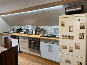 a kitchen with white cabinets and a white refrigerator at L Atypik à L ancienne forge in Muhlbach-sur-Munster