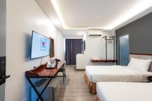 Habitación de hotel con 2 camas, escritorio y TV. en Luck Thai Hotel en Chiang Mai