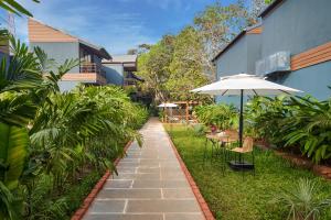 a walkway with chairs and an umbrella in a yard at Avataara Resort & Spa in Anjuna