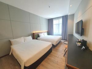 Habitación de hotel con 2 camas y TV de pantalla plana. en Ceria Hotel en Kuala Lumpur