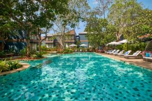 basen w ośrodku z krzesłami i drzewami w obiekcie Avataara Resort & Spa w mieście Anjuna