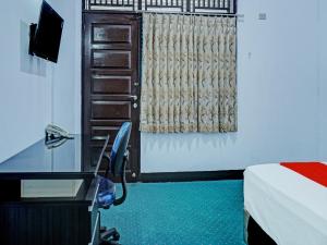 um quarto com uma secretária, uma cama, uma secretária e uma cadeira. em OYO 92189 Wisma Inayah Syariah em Palimbão