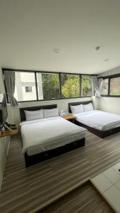 two beds in a large room with windows at 念念Nian Nian Taomi Inn in Puli