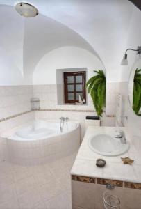 La salle de bains blanche est pourvue d'une baignoire et d'un lavabo. dans l'établissement VIP MiKU apartman 2, à Mikulov