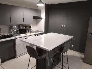 a kitchen with a white counter top and black cabinets at Au cœur du village d' Argelès-sur-Mer in Argelès-sur-Mer