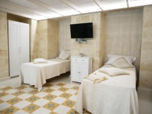 a bedroom with two beds and a tv on the wall at Casa Sant'Agata in Laterza