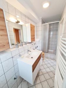 ein weißes Badezimmer mit einem Waschbecken und einem Spiegel in der Unterkunft Appartementhaus Bayern Residenz in Bad Füssing
