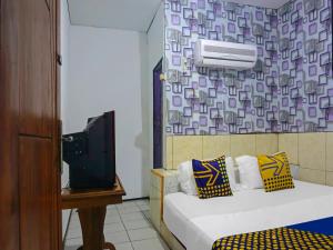 a small room with two beds and a tv at SPOT ON 92154 Nusasari Guest House in Sukabumi