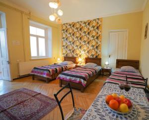 um quarto com três camas e uma tigela de fruta numa mesa em Leon Rooms em Tbilisi