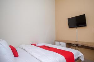 a bedroom with a bed with a television on the wall at RedDoorz Plus near UMS Solo 2 in Solo