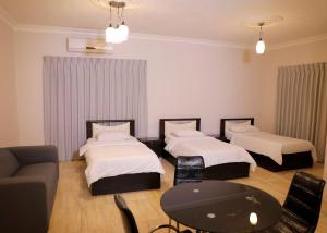 Zimmer mit 2 Betten, einem Tisch und einem Sofa in der Unterkunft Abu Alsoud Hotel in Amman