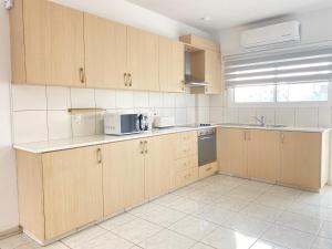 an empty kitchen with wooden cabinets and a microwave at Phaedrus Living Down Town Flat Stephania 302 in Limassol