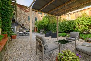 un patio con sillas, una mesa y un edificio en Il Chiostro Appartamenti & Suites, en Suvereto