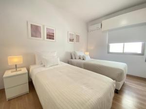 two beds in a room with white walls at Phaedrus Living Down Town Flat Stephania 302 in Limassol