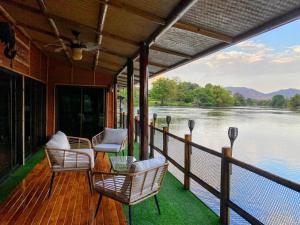 um alpendre com cadeiras e vista para o rio em The Parrot Inn Kanchanaburi em Kanchanaburi