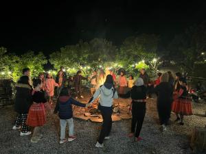 un grupo de personas bailando alrededor de un fuego por la noche en Mường sang farmstay, en Mộc Châu