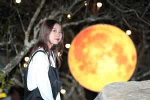 uma mulher está em pé na frente de uma grande lua em Eco House Mộc Châu em Mộc Châu