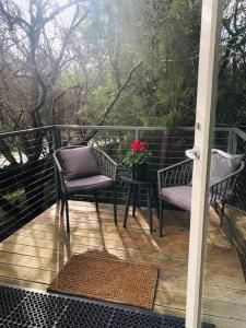 a porch with two chairs and a table with flowers at Hepburn hideaway studio in Hepburn Springs