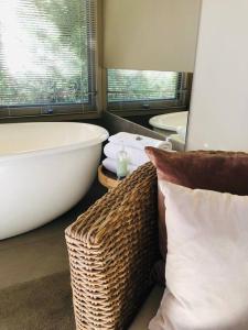 a bathroom with a large bath tub and a wicker couch at Hepburn hideaway studio in Hepburn Springs