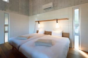 - une chambre avec un grand lit blanc et 2 oreillers dans l'établissement オーシャンビュー非日常を味わえる空間プライベートバーベキューm yomitan nagahama, à Yomitan