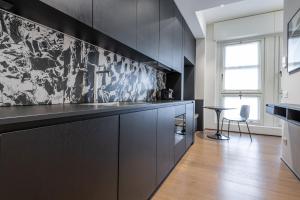 a kitchen with black cabinets and a table and a chair at Easylife - Elegante monolocale in Corso Magenta in Milan