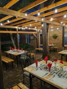 a patio with wooden tables and chairs with red roses at Gorgeous Gecko Guesthouse in Modimolle